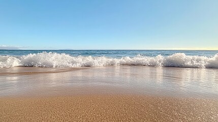 Poster - Soft ocean waves gently roll onto the shore, creating a tranquil scene of white foam meeting golden sand under a clear blue sky, offering a serene coastal view