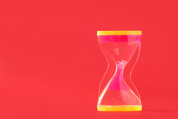 Wall Mural - Stylish modern hourglass with pink sand on red background