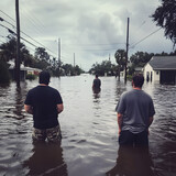 People standing in waist high flood water after a Hurricane