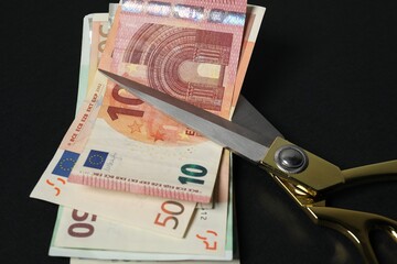 Wall Mural - Euro banknotes and scissors on black background, closeup