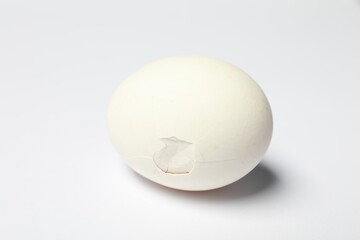 Wall Mural - One egg with cracked shell on white background, closeup