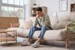 © Pixel-Shot - Worried young man sitting on sofa  at home