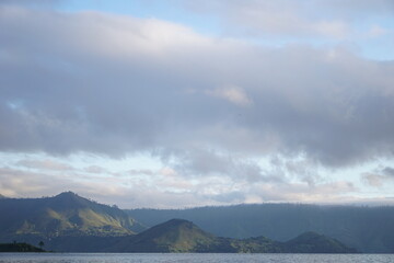 Boat with fishermen looking for fish in the lake, beautiful view, vast landscape of Lake Toba, with beautiful mountains, in the morning with the sun shining 