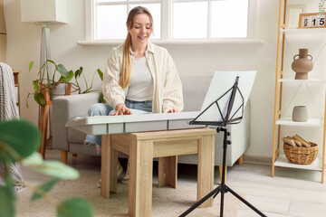 Wall Mural - Young woman playing synthesizer at home