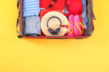 Sticker - Travel abroad. Packed suitcase on yellow background, top view. Space for text