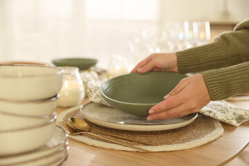 Woman setting table for dinner at home, closeup