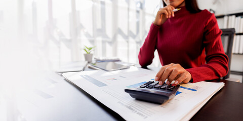 Wall Mural - Business financing accounting banking concept. Business woman hand doing finances and calculate on desk about cost at home office. Woman working on desk with using calculator, finance accounting.
