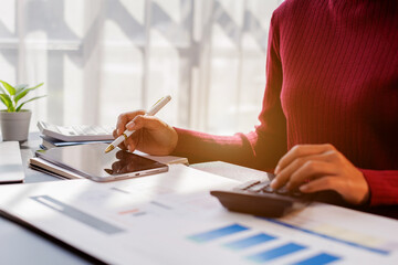 Wall Mural - Business financing accounting banking concept. Business woman hand doing finances and calculate on desk about cost at home office. Woman working on desk with using calculator, finance accounting.
