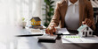© David - Business mortgage realtor with house model, sitting at desk, real estate agent manager working on calculator and documents, mortgage and property.
