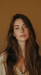 Aufkleber - A woman stands confidently with long brown hair cascading gracefully, illuminated by a warm tan background that enhances her natural glow and serene expression, embodying effortless beauty