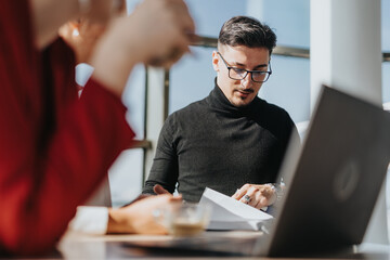 Wall Mural - A group of business people engaged in discussion around a table in a contemporary office kitchen environment.