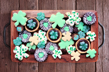 Canvas Print - St Patricks Day shamrock dessert board. Green cookies and sweets. Top view over a rustic wood background.