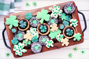 Poster - St Patricks Day shamrock dessert board. Green cookies and sweets. Top view table scene over a white wood background.