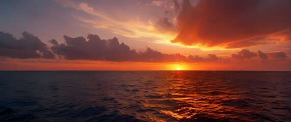 Wall Mural - A radiant sunset illuminating the horizon over tranquil waters where the sky merges with the sea in a dazzling display of fiery colors