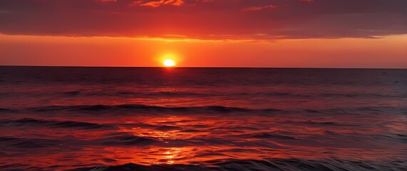 Wall Mural - A picturesque red sunset wrapping around the tranquil horizon of the sea casting vibrant reflections that dance upon the gentle waves below