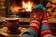 © abdul - Cozy winter scene close up of woolen socks by a christmas fireplace with a woman enjoying a drink