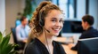 © Here you are! - Professional female call center agent with curly hair, wearing a headset and smiling warmly in a busy, well-lit office environment with a welcoming and approachable demeanor