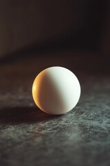 Poster - Close-up of a single, smooth, white sphere on a dark, textured surface.