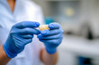 © inas - Dental professional holding a dental crown with blue gloves