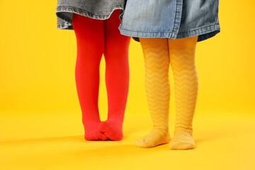 Wall Mural - Kids wearing colorful tights on orange background, closeup