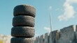 © NoorZafirah - Stack of Four Used Tires Against Blue Sky and Industrial Background in Outdoor Setting