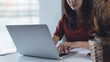 © tippapatt - Asian woman working on laptop computer at home office. Business woman typing on notebook computer, surfing the net, searching the information, online working at home, closeup