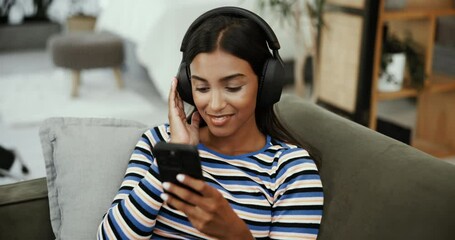 Fototapete - Phone, music and happy woman relax with headphones in home for edm album, song and listening to radio. Mobile, online audio and girl on sofa to scroll app, streaming service or typing social media