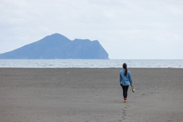 Wall Mural - Woman Walking Alone on Beach Toward Distant Island