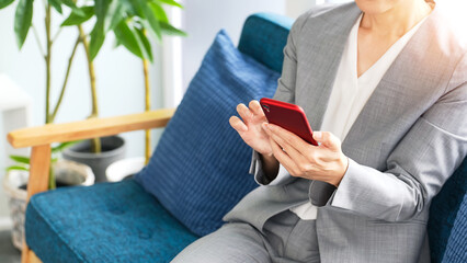 Leinwandbilder - スマホ、スマートフォン、女性、ビジネスウーマン、日本人、ビジネス、携帯電話、SNS、検索、メール、ニュース、アプリ、スーツ、ビジネスパーソン、ソファー、座る、リラックス、コピースペース、インターネット、オンライン、web、通信、動画、ブラウザー、投稿、DX、デジタル、ツール、データ、笑顔、お得、クーポン、ポイント、ネットショッピング、キャンペーン、X、オフィス、リビング、ロビー、予約、連絡、仕事、