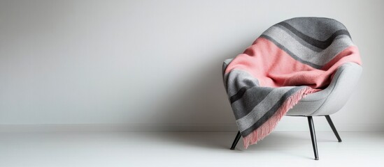 Poster - Inviting armchair with grey and pink striped blanket on white backdrop emphasizing minimalistic design and ample space for text insertion