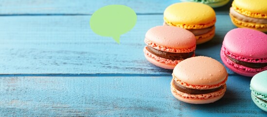 Wall Mural - Colorful Macaron Cookies Displayed on Rustic Blue Wooden Background with Speech Bubble for Creative Culinary Presentation