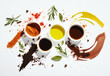 © ลลิดา ไชยศรีษะ - A flat lay of various spices and herbs on a white background, with olive oil in small bowls scattered around. The colors include reds, oranges, yellows, greens, and brown tones, creating an