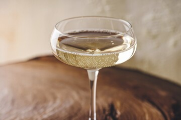 Poster - A glass of sparkling wine sits on a wooden surface, bubbles rising to the top.
