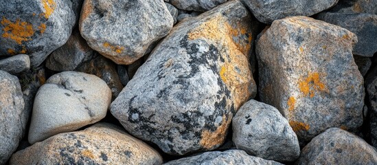 Poster - Textured arrangement of gray granite stones with yellow-orange lichen patterns creating a natural background for design projects.