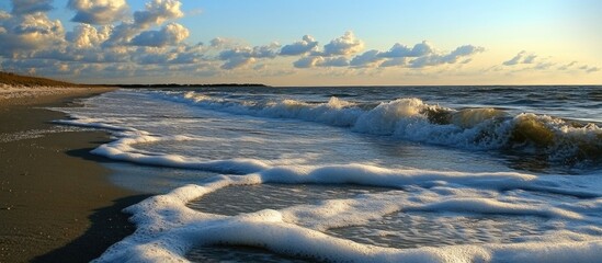 Poster - Tranquil beach scene at sunset with gentle waves and sea foam creating a serene coastal atmosphere.