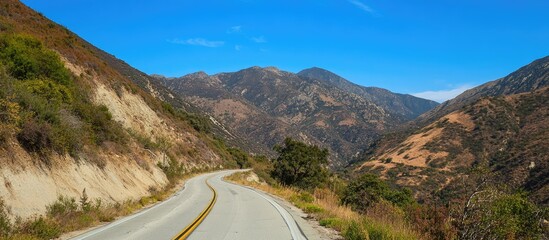 Canvas Print - Scenic winding road through Sierra Limena mountains surrounded by green and brown landscapes under a clear blue sky