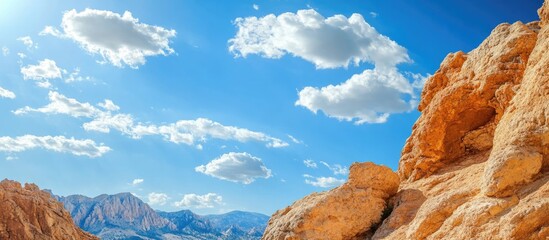 Aufkleber - Rock formations against a bright blue sky with fluffy clouds and space for text ideal for nature-themed designs and advertisements