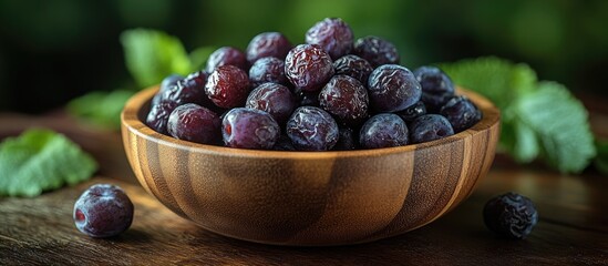 Canvas Print - Natural Dried Plums Prunes in Wooden Bowl Surrounded by Fresh Green Leaves Perfect for Healthy Snack and Cooking Uses