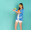 © sitthiphong - Songkran festival in Thailand, Full body length happy smiling young Asian woman in summer wearing floral shirt with plastic glasses and holding water guns in blue background.