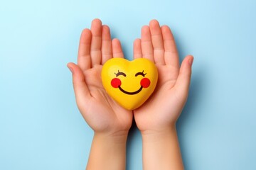 Poster - A hand holds a bright yellow heart with a cheerful smiley face, great for expressing love and positivity