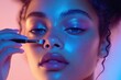 © hkjdesign - Close-up of a woman's face with vibrant neon makeup and glitter, applying makeup with a brush.