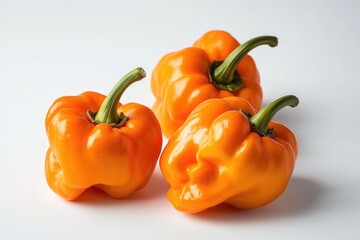 Poster - Three orange peppers placed neatly on a white surface, perfect for still life photography or kitchen decoration