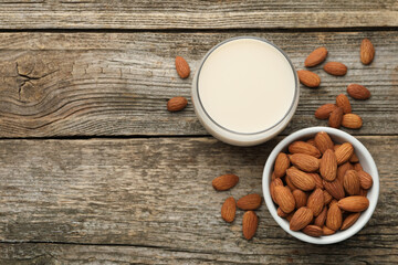 Wall Mural - Fresh almond milk in glass and nuts on wooden table, top view. Space for text