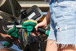 © Kirill Gorlov - Close--up woman casual outfit hand hold fuel pump nozzle refuel car gas station sunny summer day. Confident female person filling auto tank fuel holding fuel nozzle enjoy travel vacation journey trip