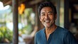 © Wilasinee - Portrait of a confident and joyful Asian man captured in a relaxed natural outdoor setting with a wood background  The image showcases the man s positive emotion middle aged adult character