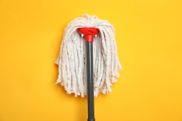 Wall Mural - String mop on yellow background, top view