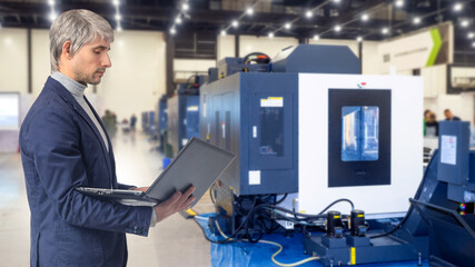 Poster - industrial cnc machine. man with laptop in factory building. control cnc equipment via computer. clo