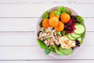 Wall Mural - Healthy homemade salad bowl with falafels, hummus, quinoa and vegetables. Top view on a white wood background.