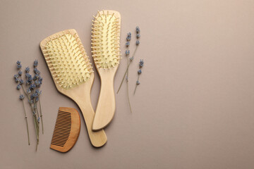 Wall Mural - Wooden hair brushes, comb and lavender flowers on color background, flat lay. Space for text