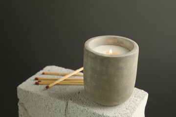 Wall Mural - Burning soy wax candle and matches on concrete block against gray background, space for text